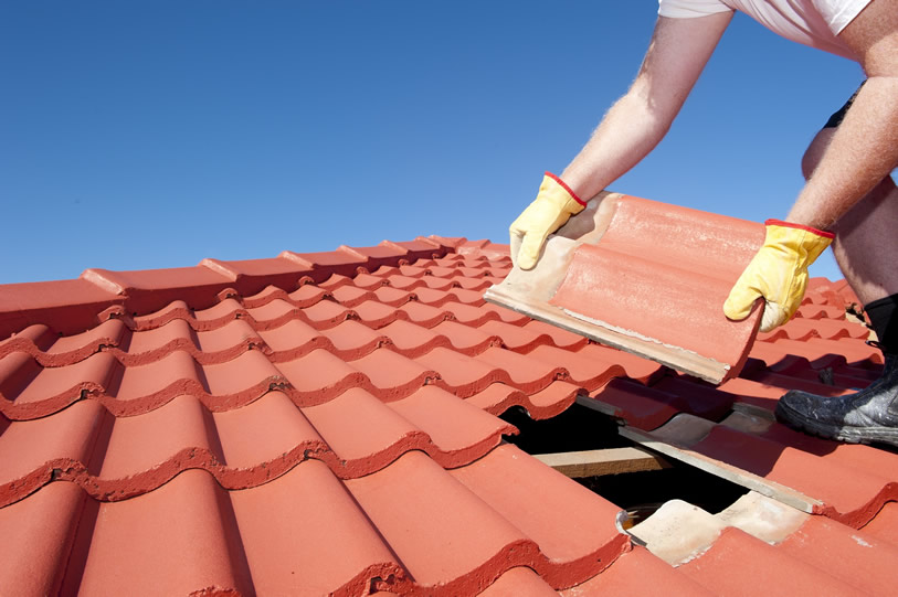 A roofer replacing a broken terracotta tile